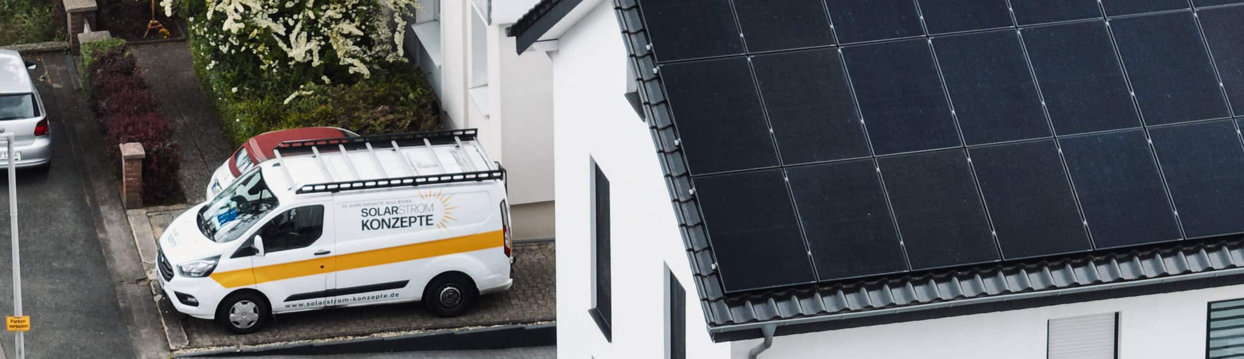 Einsatzfahrzeug von Solarstrom Konzepte parkt neben einem Einfamilienhaus mit frisch installierter Photovoltaikanlage auf dem Ziegeldach – hochwertige Solarmodule für nachhaltige Energiegewinnung im Wohngebiet