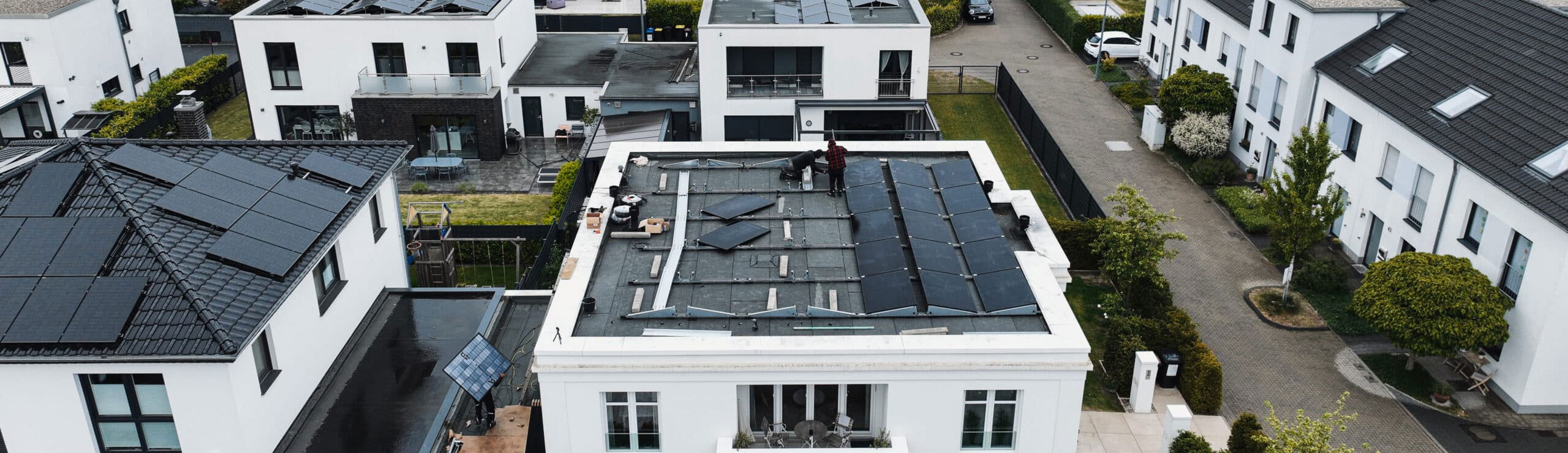 alt="Moderne Photovoltaikanlage auf Flachdach in der Aufbauphase mit sichtbaren Montageschienen und installierten Solarmodulen."
